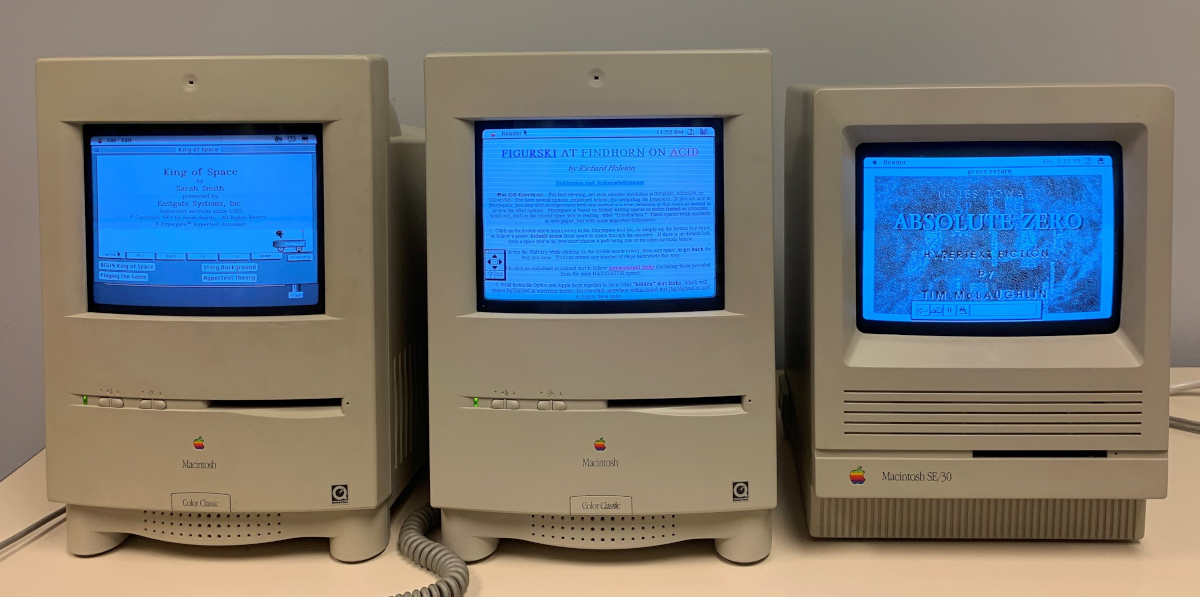Three beige compact Macs displaying hypertext artwork